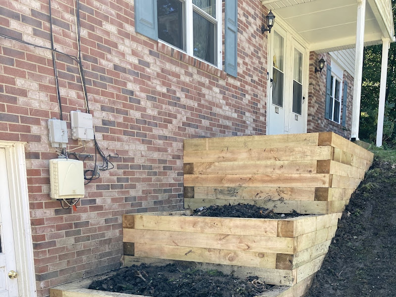 Tiered timber retaining wall and planter box built against a sloped house foundation, a real Retaining Walls LLC job